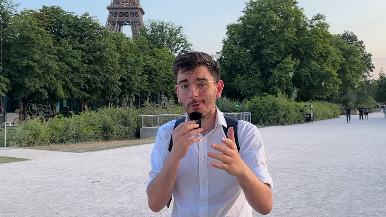 Steven Klinger en tournage extérieur devant la tour Eiffel, micro à la main, pendant la vidéo sur les applications de rencontre.